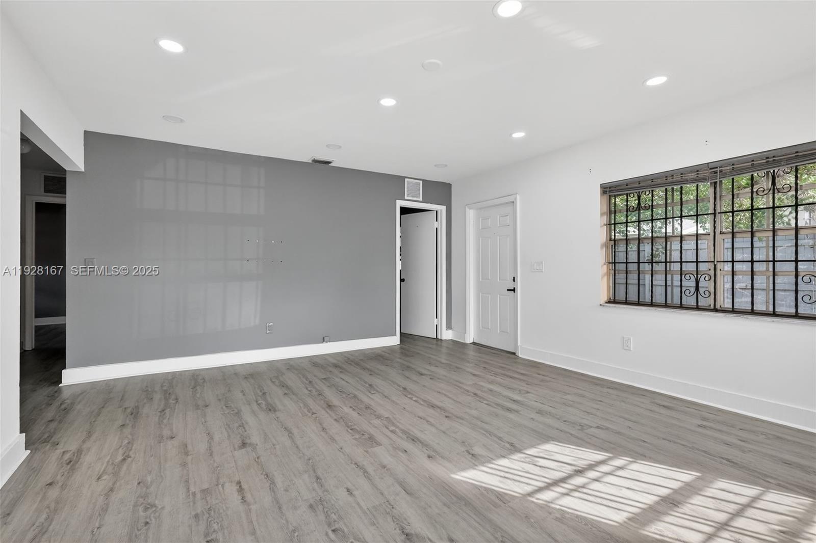 708 Southwest 10th Street, Unit 1 Dania Beach, FL 33004 - Photo 8 of 23 an empty room with wooden floor and windows