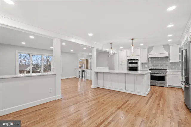 a kitchen with stainless steel appliances kitchen island wooden floors and white cabinets