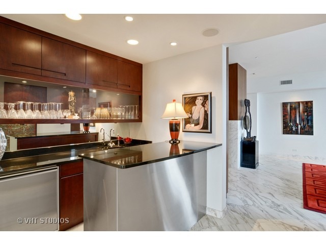 910 South Michigan Avenue, Unit 1101 Chicago, IL 60605 - Photo 17 of 20 a kitchen with granite countertop a stove a sink and a wooden cabinets