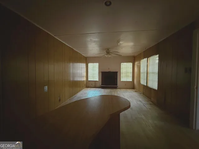 a view of empty room with wooden floor and fan
