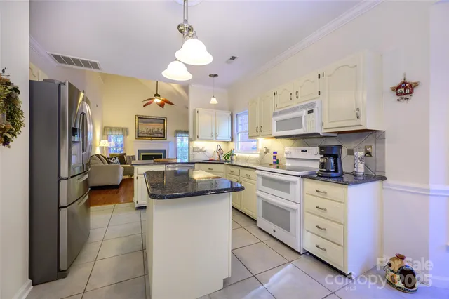 a kitchen with stainless steel appliances kitchen island granite countertop a refrigerator and a sink