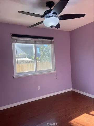 a view of an empty room with wooden floor and windows
