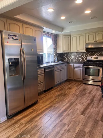 a kitchen with stainless steel appliances granite countertop a refrigerator a sink and wooden cabinets