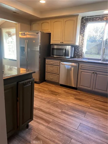 a kitchen with granite countertop a refrigerator a sink and dishwasher with wooden floor