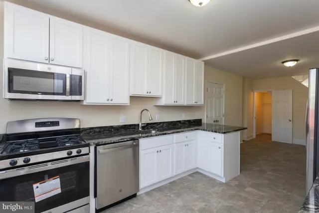 a kitchen with granite countertop white cabinets and stainless steel appliances
