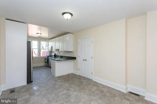 a kitchen with a refrigerator and white cabinets