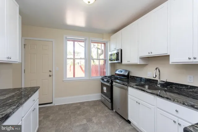 a kitchen with granite countertop white cabinets and appliances