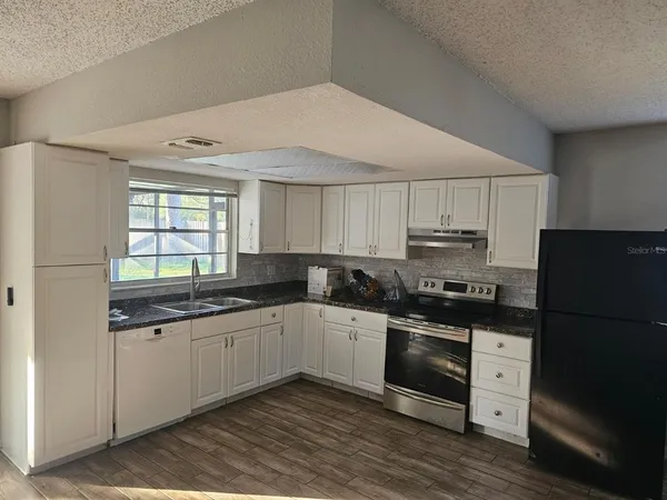 a kitchen with stainless steel appliances a sink a stove a refrigerator and cabinets