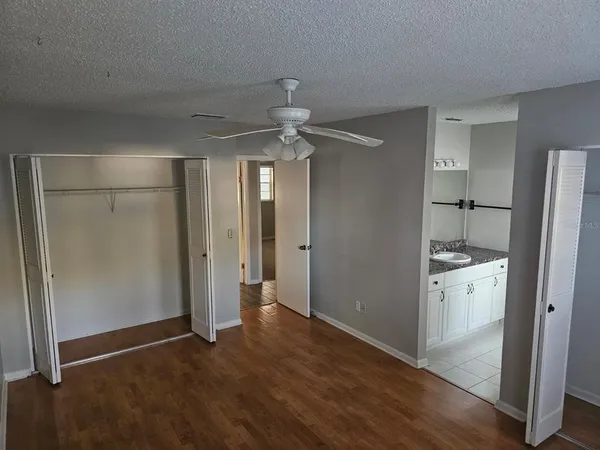 an empty room with wooden floor and a ceiling fan