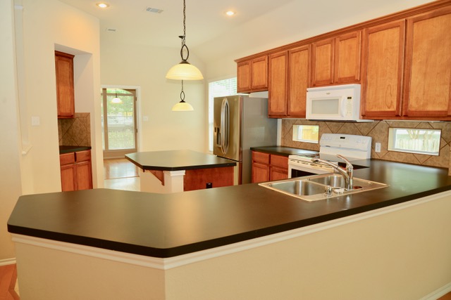 138 Chestnut Court Georgetown, TX 78633 - Photo 7 of 25 A well-lit culinary space features abundant wood cabinetry and dual kitchen islands for effortless meal preparation.