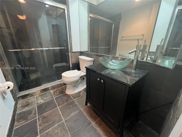 a bathroom with a granite countertop sink toilet and shower