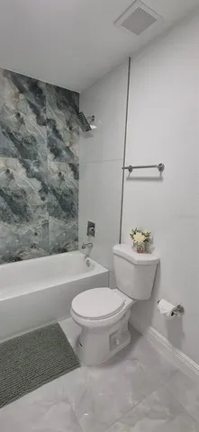 a white toilet sitting next to a bath tub