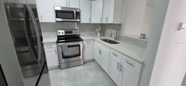a kitchen with white cabinets and stainless steel appliances