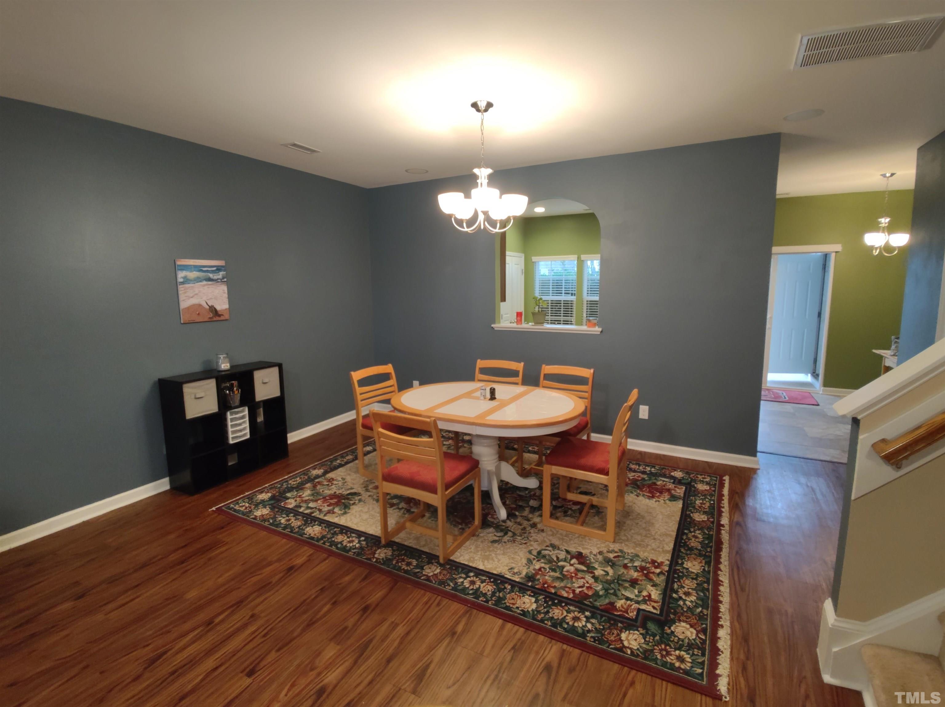 1125 Ileagnes Road Raleigh, NC 27603 - Photo 25 of 27 a dining room with wooden floor a chandelier a wooden table and chairs