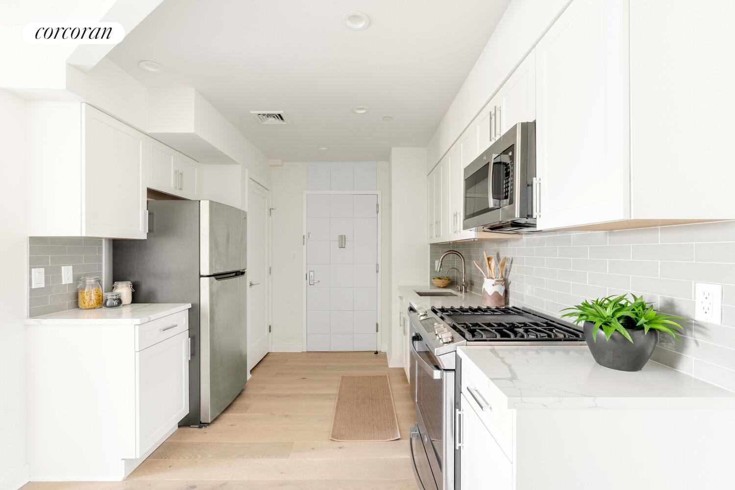 23-23 30th Road, Unit 4C Queens, NY 11102 - Photo 4 of 10 a kitchen with stainless steel appliances a sink a stove a microwave a refrigerator a sink and cabinets