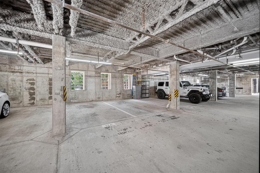 5015 Meridian Lane, Unit 2102 Addison, TX 75001 - Photo 32 of 36 Spacious concrete parking garage featuring exposed overhead ductwork, multiple support columns, perimeter windows, and overhead strip lighting