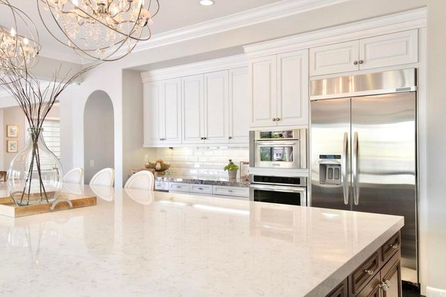 a large kitchen with stainless steel appliances a large center island attached withe living room