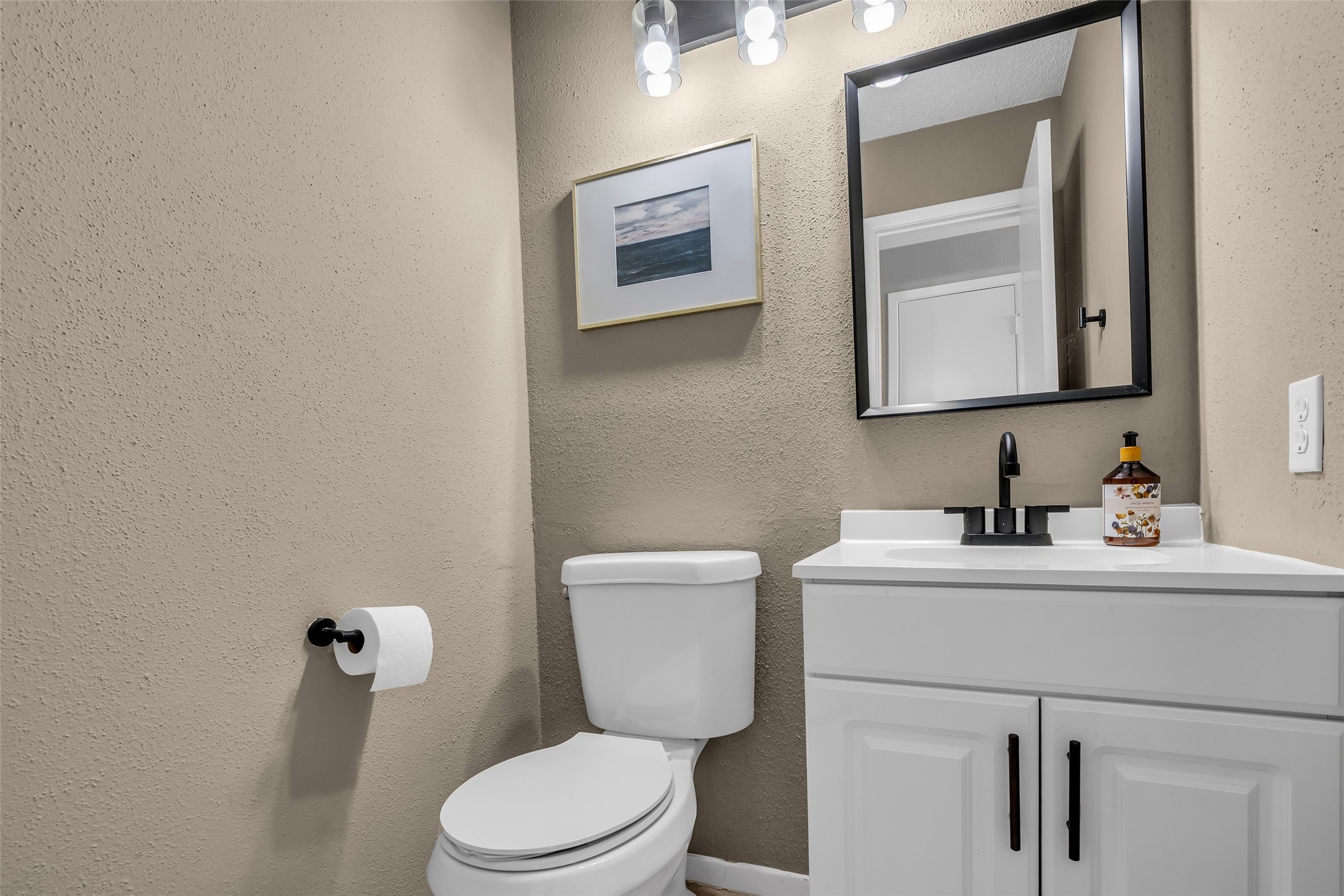 9415 Towerstone Drive Spring, TX 77379 - Photo 26 of 41 This photo shows a bright bathroom with a double vanity featuring white cabinets and two large mirrors. It opens to a cozy bedroom with a wooden bed frame and a ceiling fan.