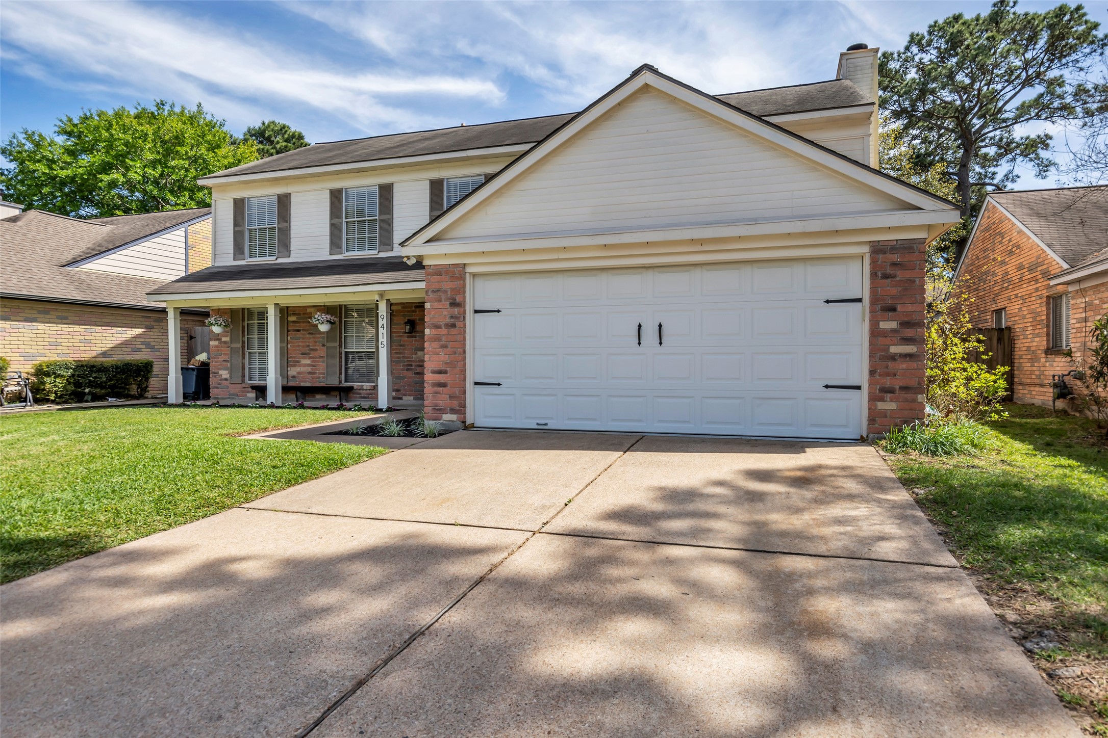 9415 Towerstone Drive Spring, TX 77379 - Photo 7 of 41 This photo showcases a welcoming entryway leading into a cozy dining room. The space features neutral walls, a tiled entrance, and warm wood floors in the dining area. A wooden console with decorative items and a round mirror adds charm, while a modern chandelier highlights the dining table set against an elegant landscape painting.