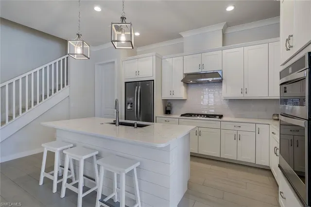 a kitchen with stainless steel appliances kitchen island a table chairs sink and cabinets