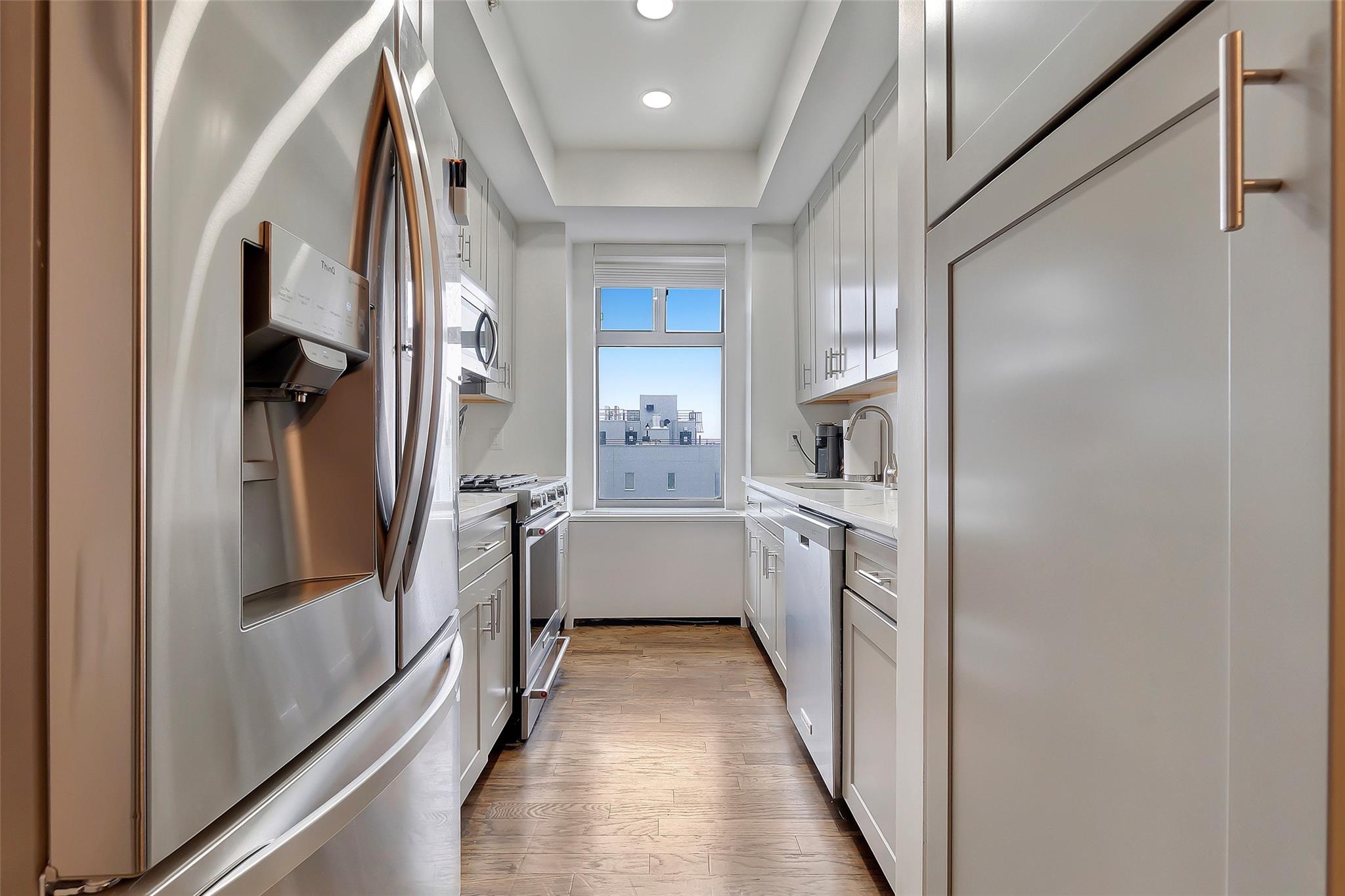 151 Beach 96th Street, Unit 5D Queens, NY 11693 - Photo 5 of 18 Kitchen featuring light countertops, white cabinets, appliances with stainless steel finishes, a sink, and light wood-style floors