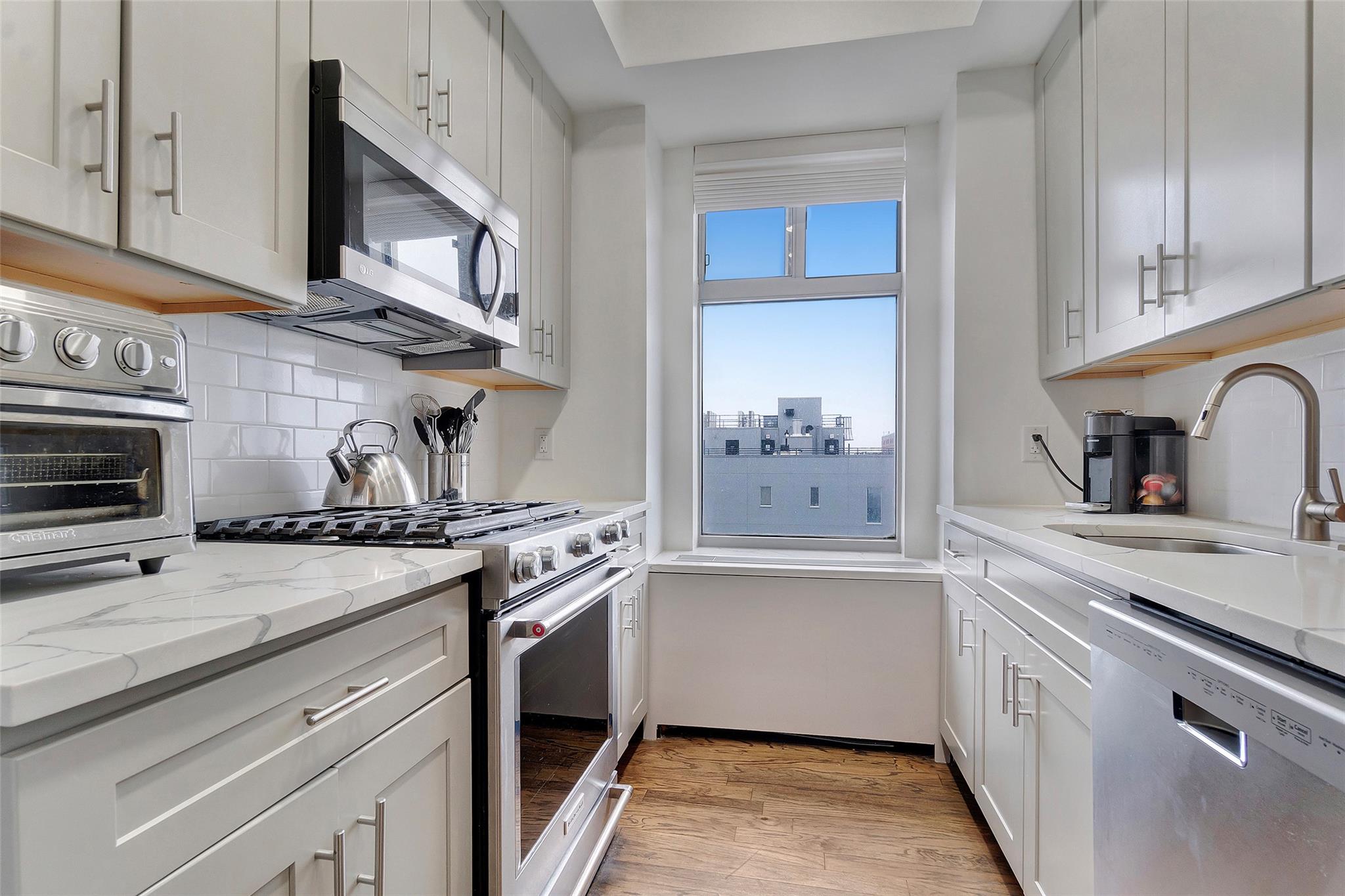 151 Beach 96th Street, Unit 5D Queens, NY 11693 - Photo 6 of 18 Kitchen with a sink, light wood finished floors, tasteful backsplash, light stone countertops, and appliances with stainless steel finishes