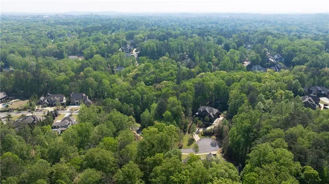 an aerial view of a house with a lush green forest