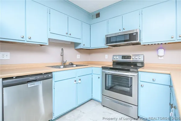 a kitchen with cabinets stainless steel appliances and sink