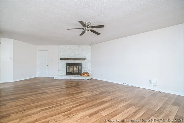 a view of empty room with wooden floor and fireplace