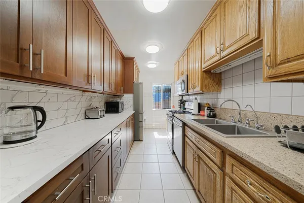 a kitchen with kitchen island granite countertop a sink stainless steel appliances cabinets and a counter top space