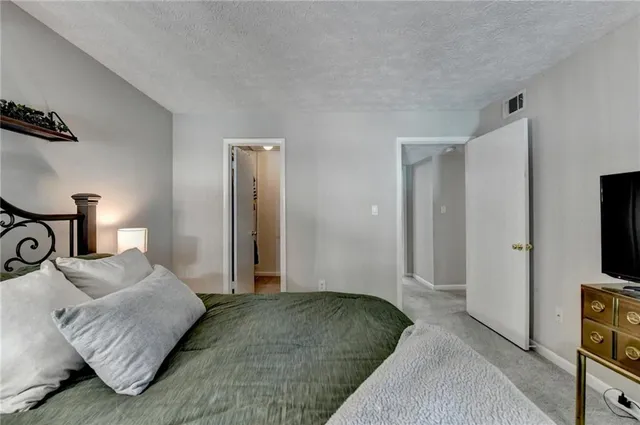 a bedroom with a bed and a flat tv screen on a dresser