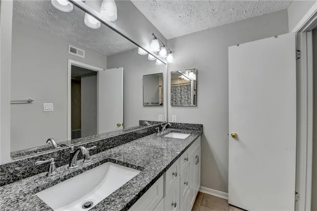 a bathroom with a granite countertop double vanity sink and a mirror