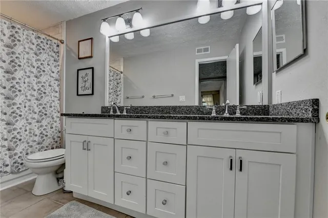 a bathroom with a granite countertop sink a toilet and a mirror