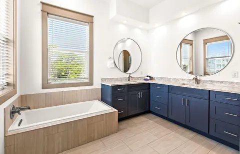 a spacious bathroom with a granite countertop tub a double vanity sink and a large mirror