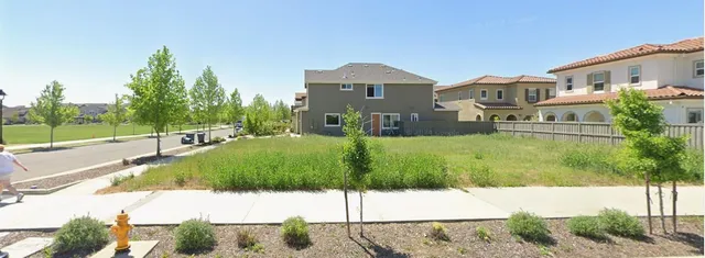 a view of a white house with a yard and plants