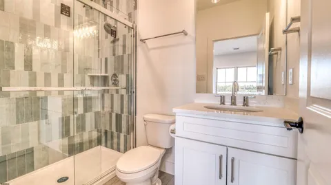 a bathroom with a sink a toilet a glass door and shower