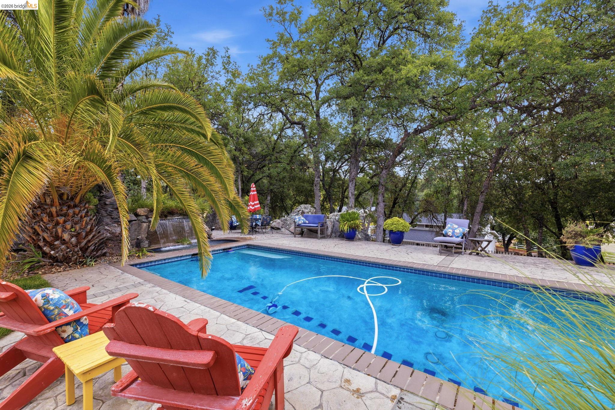 18450 Lambert Lake Road Sonora, CA 95370 - Photo 66 of 87 Outdoor swimming pool surrounded by a textured stone patio and mature trees