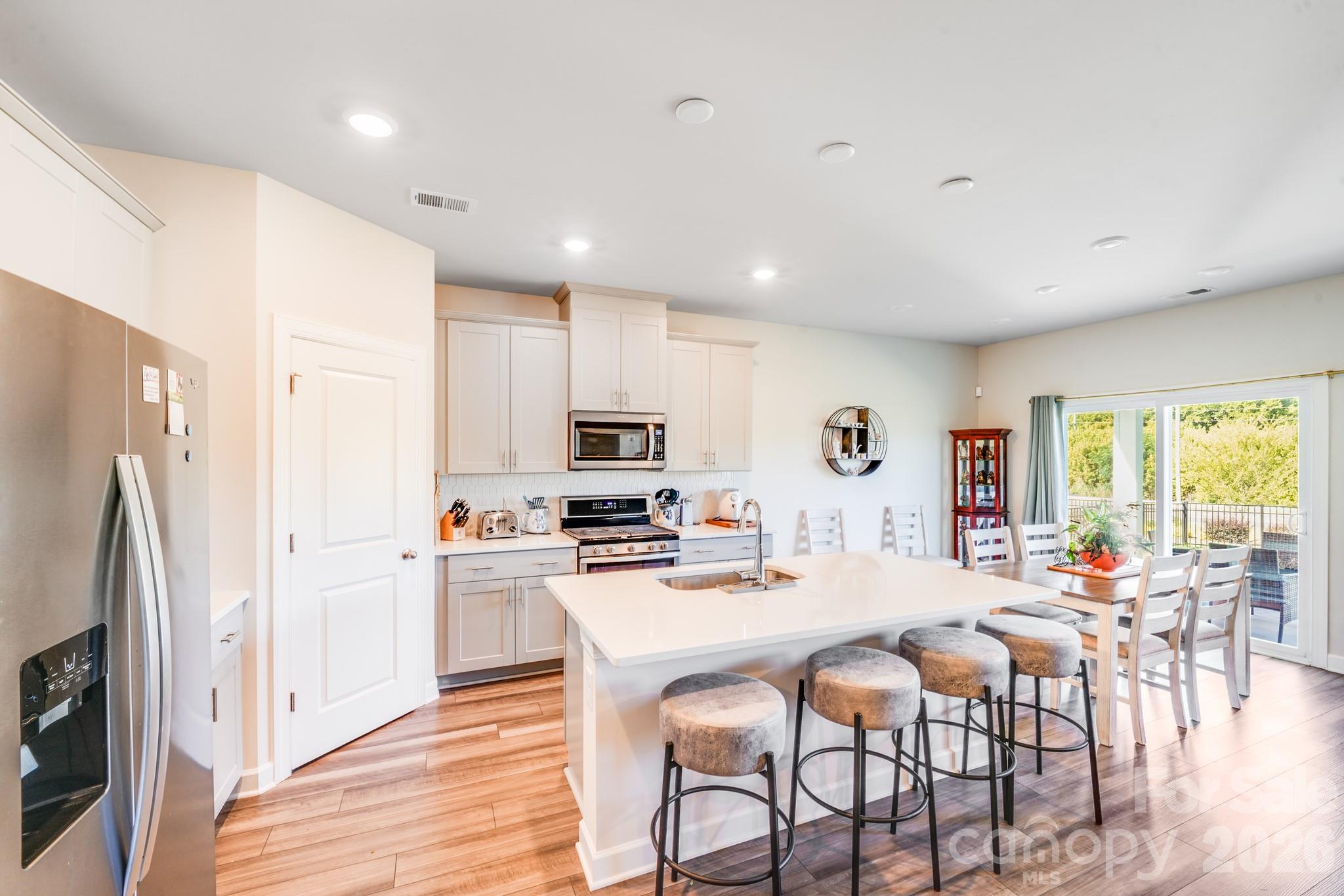 1340 Sweet Pea Street Monroe, NC 28110 - Photo 13 of 32 a view of kitchen with stainless steel appliances granite countertop a stove a refrigerator a kitchen island a table and chairs with wooden floor