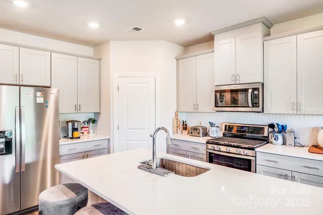 a kitchen with stainless steel appliances granite countertop a refrigerator and a stove top oven