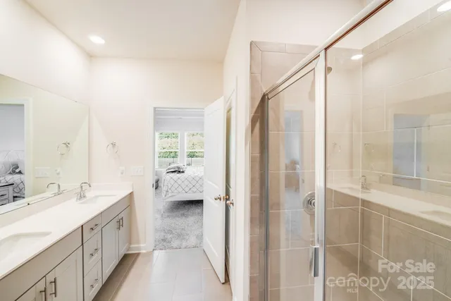 a spacious bathroom with a double vanity sink a mirror and a shower