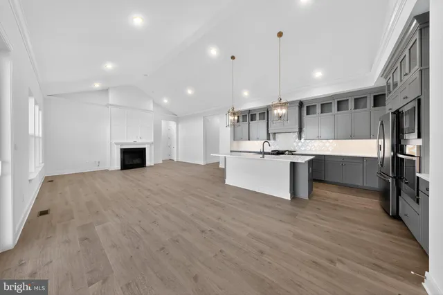 a view of kitchen with kitchen island a sink wooden floor and stainless steel appliances