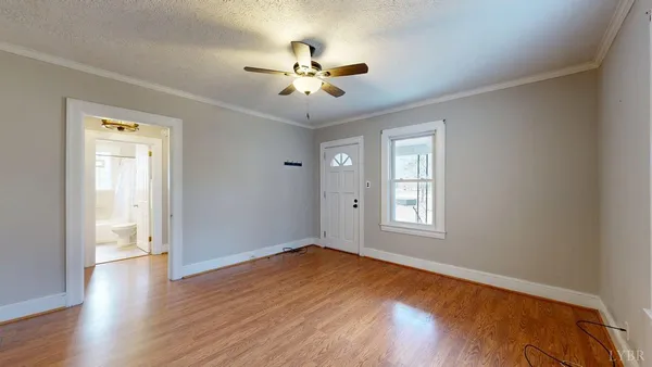 a view of empty room with wooden floor and fan