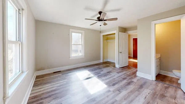 a view of empty room with wooden floor and fan