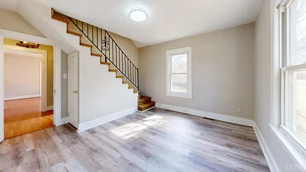 a view of an empty room with wooden floor and a window