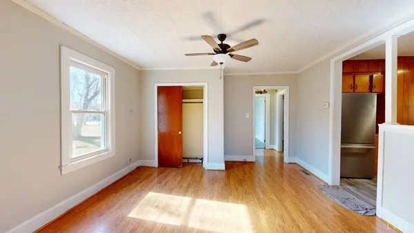 a view of empty room with wooden floor and fan