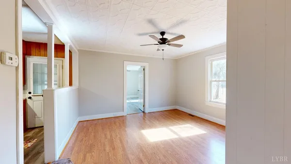 a view of empty room with wooden floor and fan