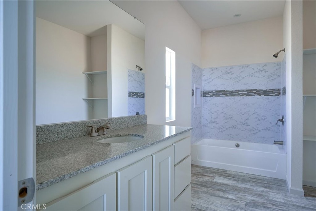 12594 Atsina Road Phelan, CA 92371 - Photo 19 of 37 a bathroom with a granite countertop sink a mirror and a bathtub