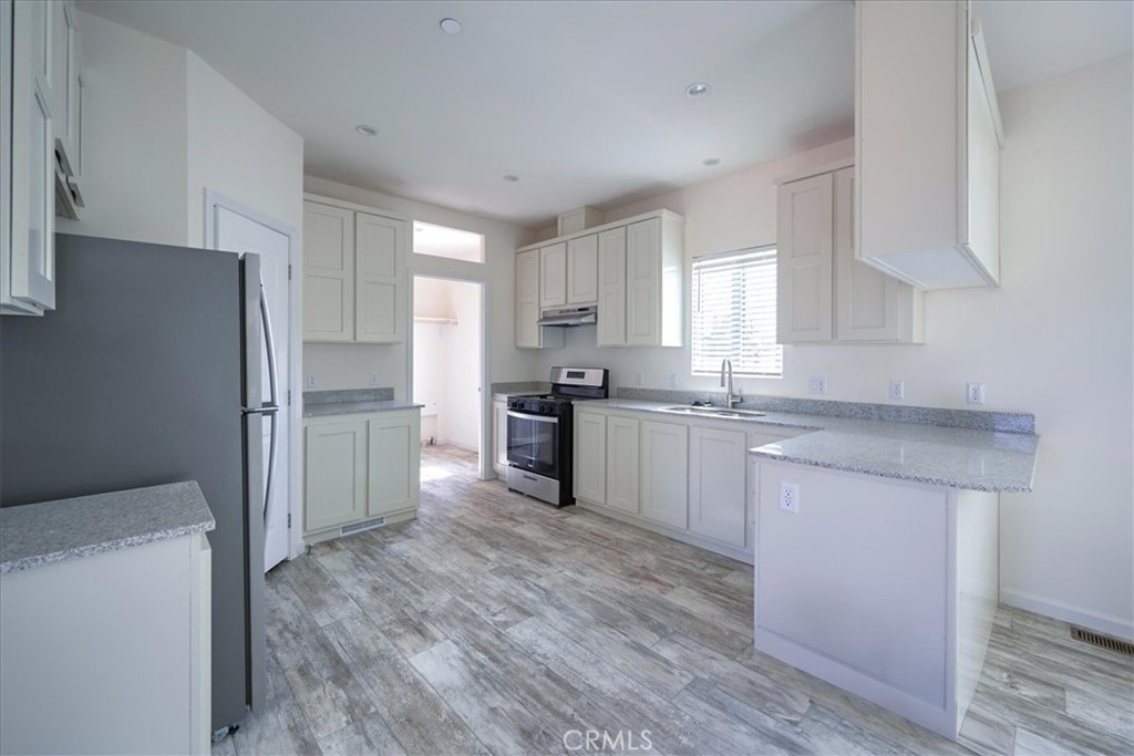 12594 Atsina Road Phelan, CA 92371 - Photo 10 of 37 a kitchen with granite countertop white cabinets and stainless steel appliances