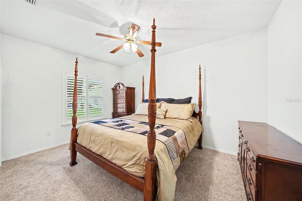 19216 Ridgelake Drive Lutz, FL 33549 - Photo 24 of 31 a bedroom with a bed a chandelier and the view of kitchen