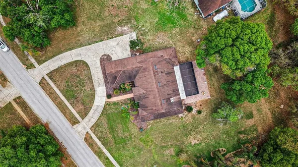 an aerial view of a house with outdoor space and trees all around